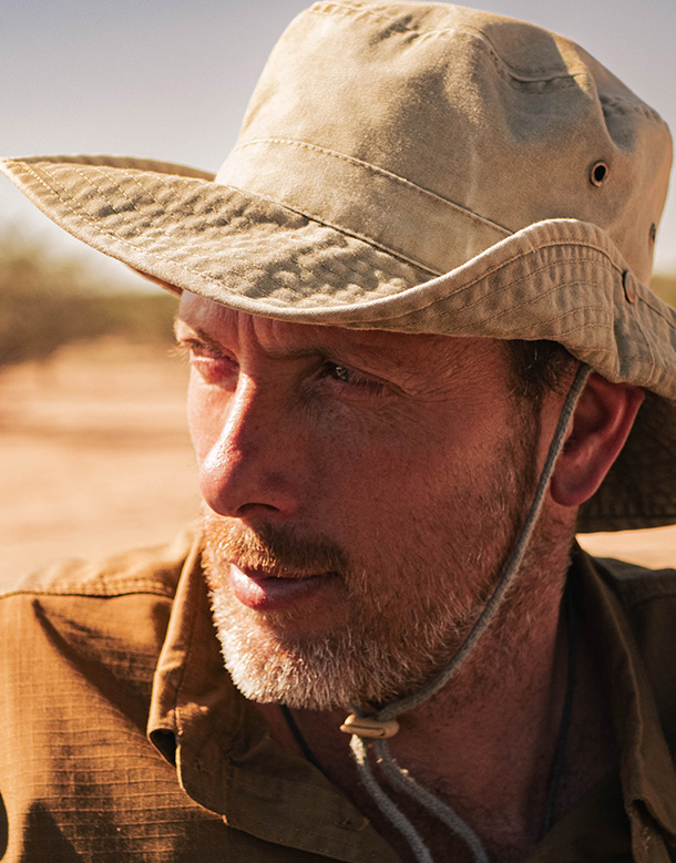 Portrait de Laurent, explorateur, portant un chapeau de brousse, regardant intensément au loin.