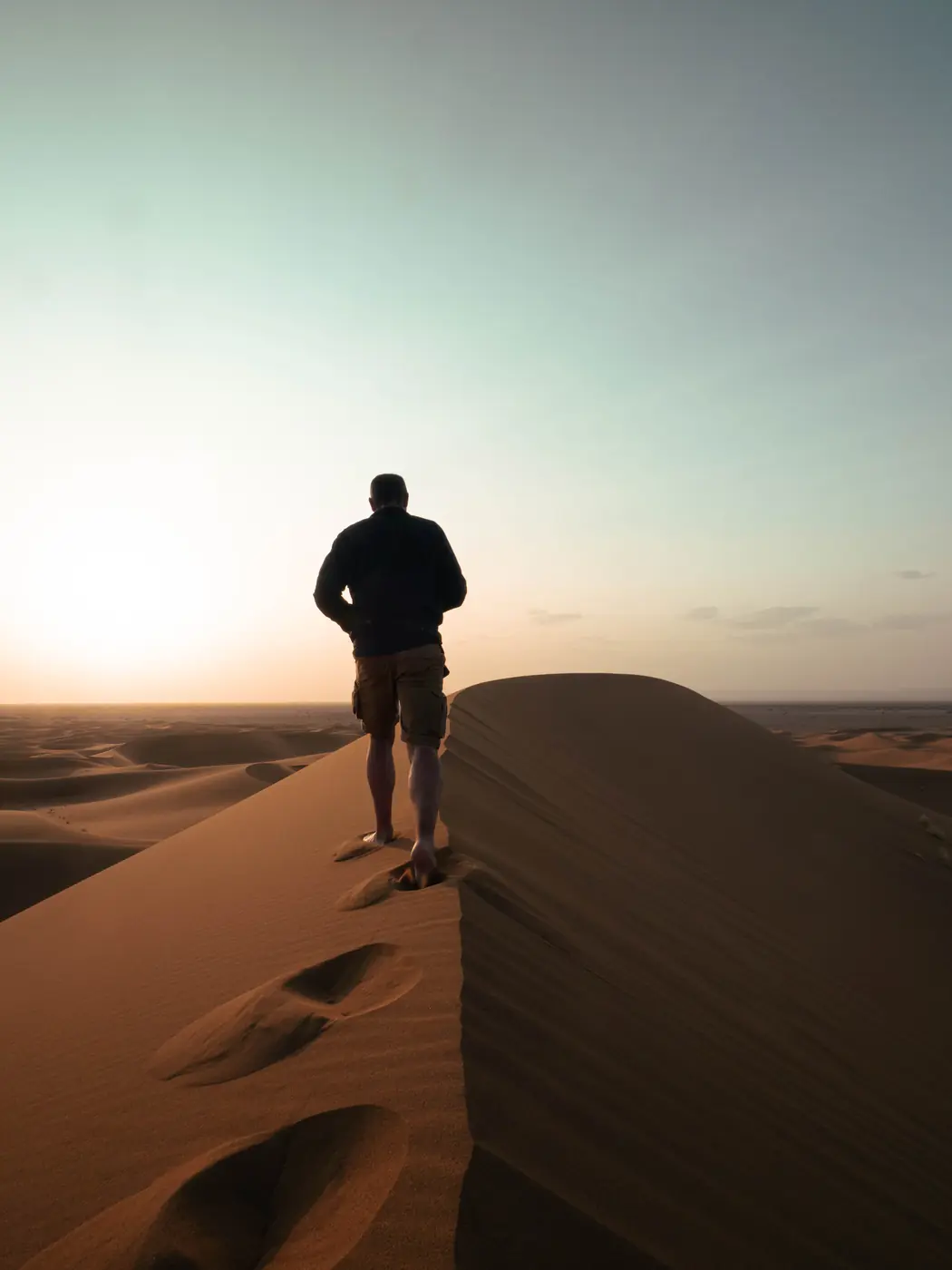 Silhouette en marche sur une crête de dune