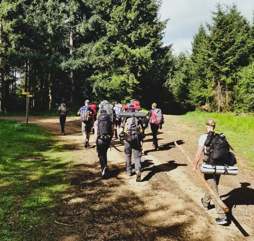 Groupe en progression sur un sentier forestier, sacs de trek